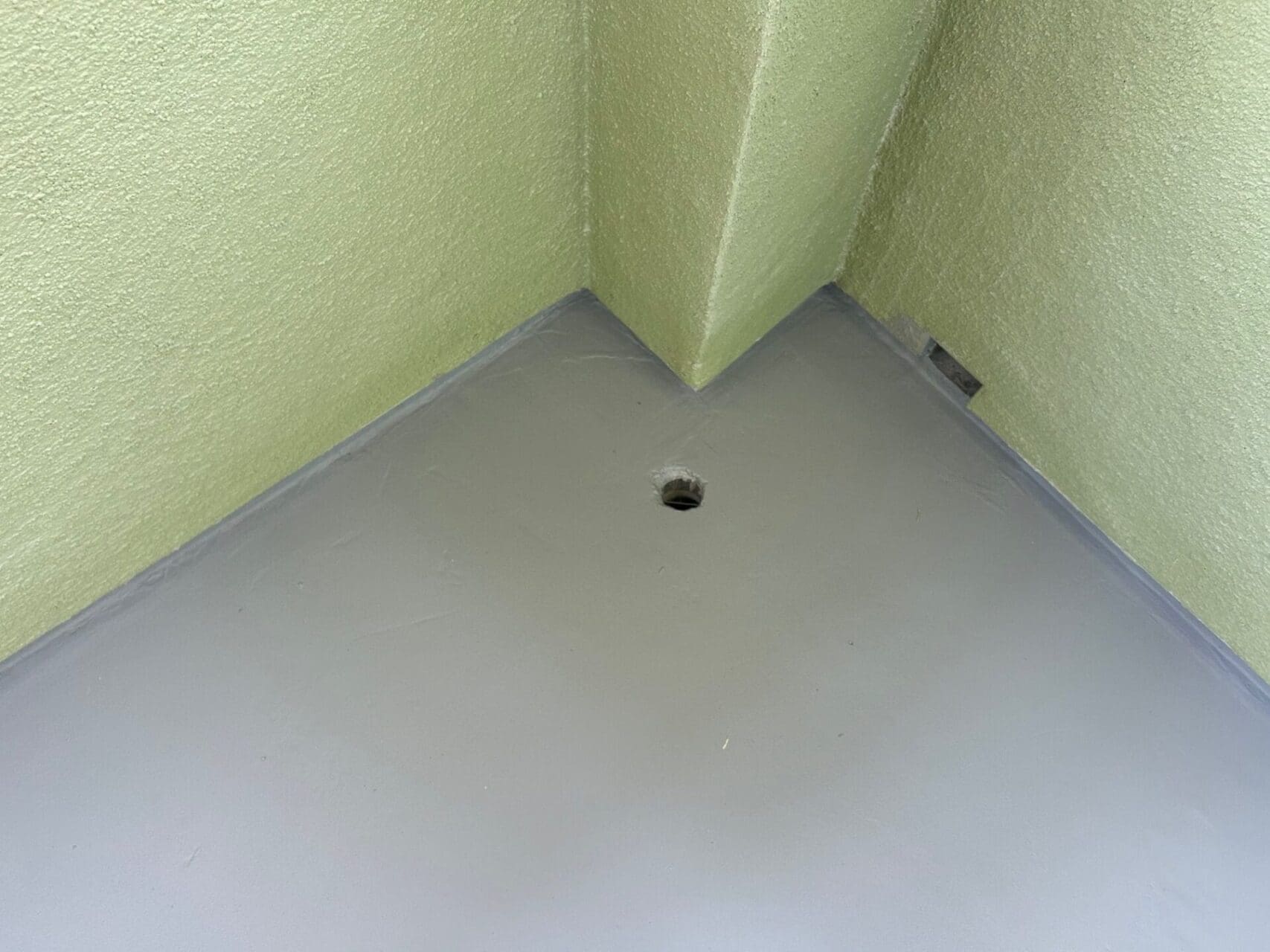 A hole in the floor of a bathroom stall.