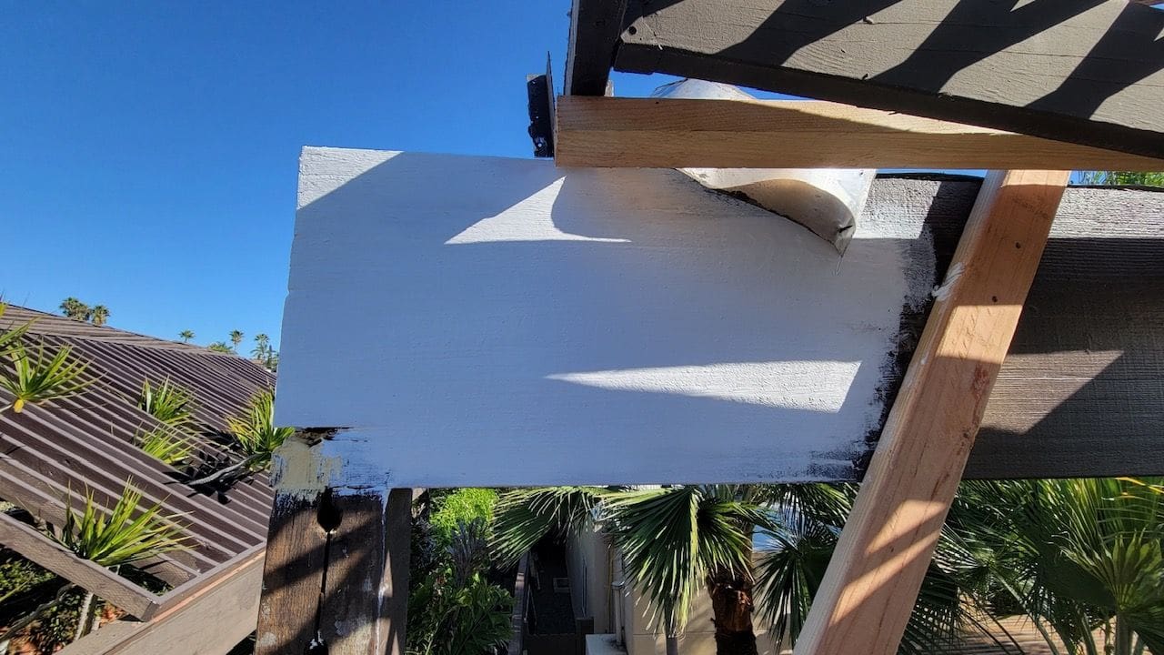 A roller is being used to paint the roof of a house.